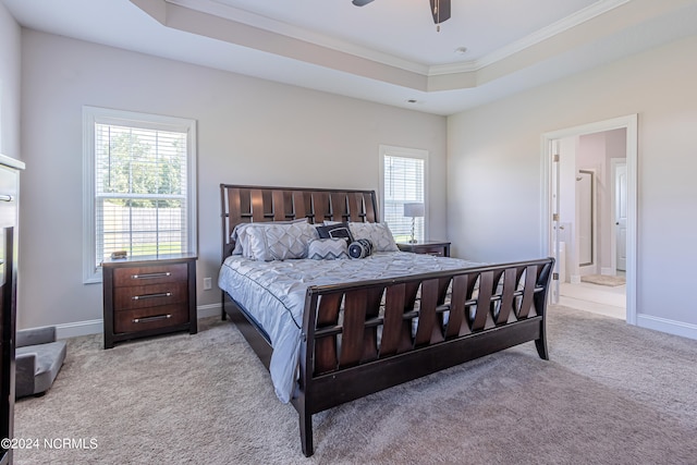 carpeted bedroom with ceiling fan, a raised ceiling, ornamental molding, and ensuite bathroom