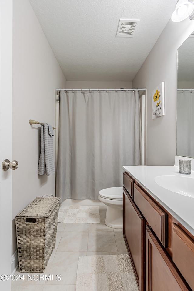 bathroom with tile patterned flooring, vanity, a textured ceiling, and toilet