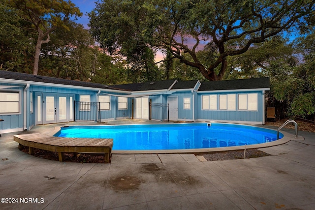 pool at dusk with a patio and french doors