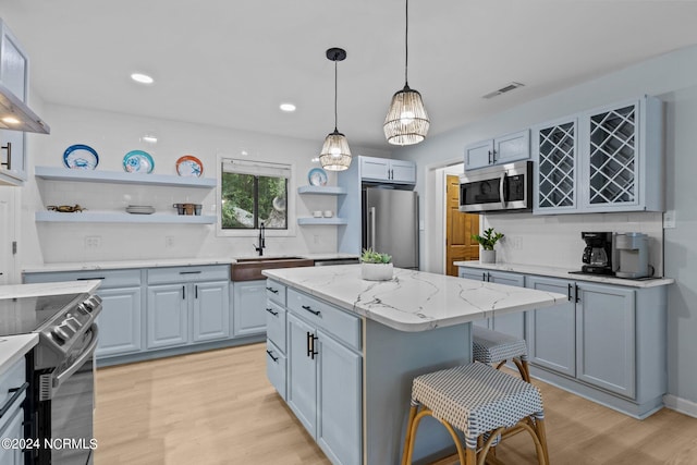 kitchen featuring pendant lighting, stainless steel appliances, light hardwood / wood-style floors, and a center island