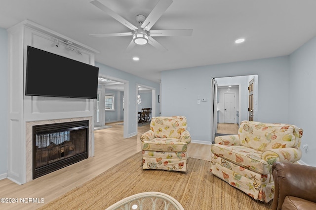 living room with light wood-type flooring, a fireplace, and ceiling fan