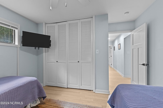 bedroom featuring ceiling fan, light hardwood / wood-style flooring, and a closet