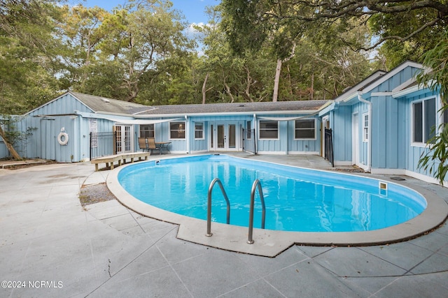 view of swimming pool featuring a storage unit, french doors, and a patio area