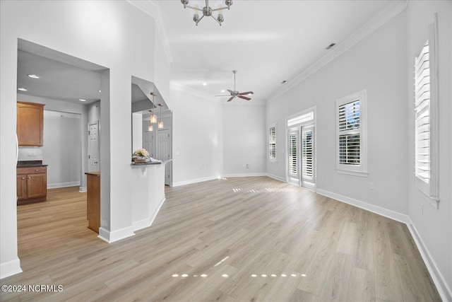 unfurnished living room with crown molding, ceiling fan, light hardwood / wood-style flooring, and a towering ceiling