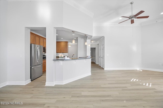 kitchen featuring hanging light fixtures, crown molding, stainless steel refrigerator, and a high ceiling