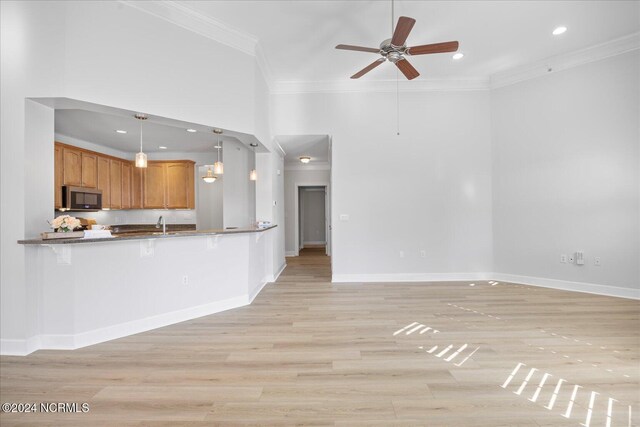 kitchen with pendant lighting, ornamental molding, kitchen peninsula, and light hardwood / wood-style flooring