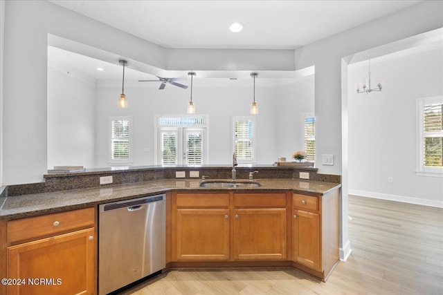 kitchen with stainless steel dishwasher, decorative light fixtures, sink, and dark stone countertops