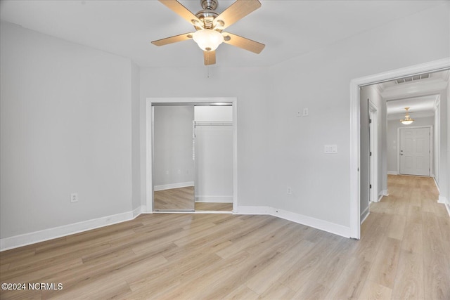 unfurnished bedroom with ceiling fan, light wood-type flooring, and a closet