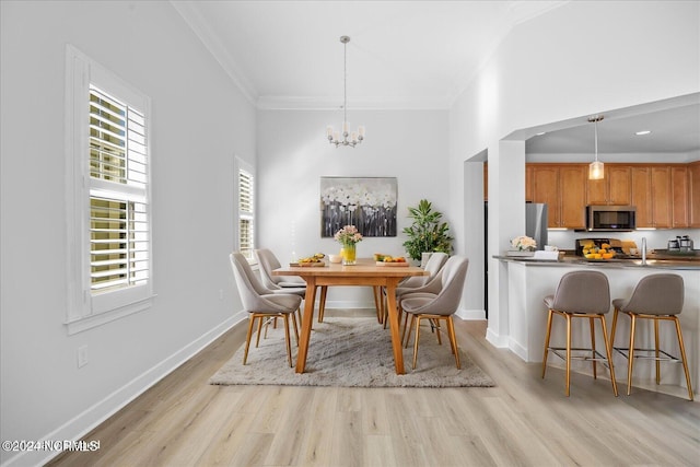 dining area with crown molding, a notable chandelier, and light wood-type flooring