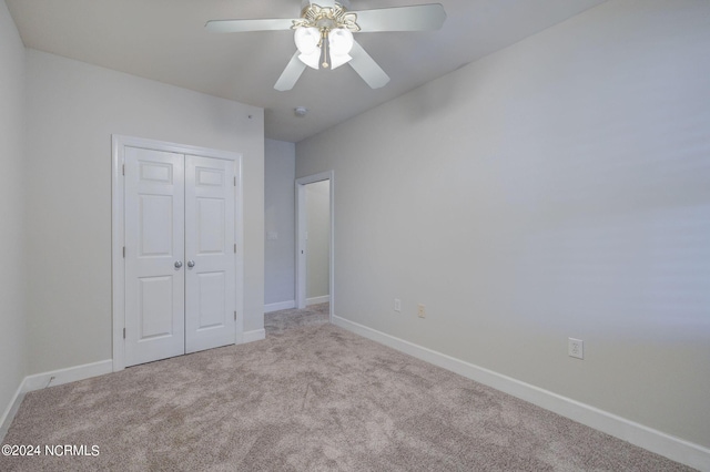 unfurnished bedroom with ceiling fan, light colored carpet, and a closet