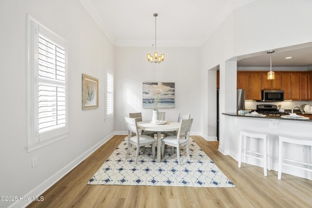 dining area featuring crown molding, sink, an inviting chandelier, and light wood-type flooring