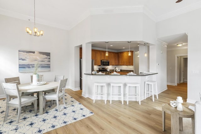 dining area featuring ornamental molding, a towering ceiling, an inviting chandelier, and light hardwood / wood-style flooring