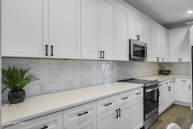 kitchen with appliances with stainless steel finishes, light stone countertops, dark hardwood / wood-style floors, and white cabinets