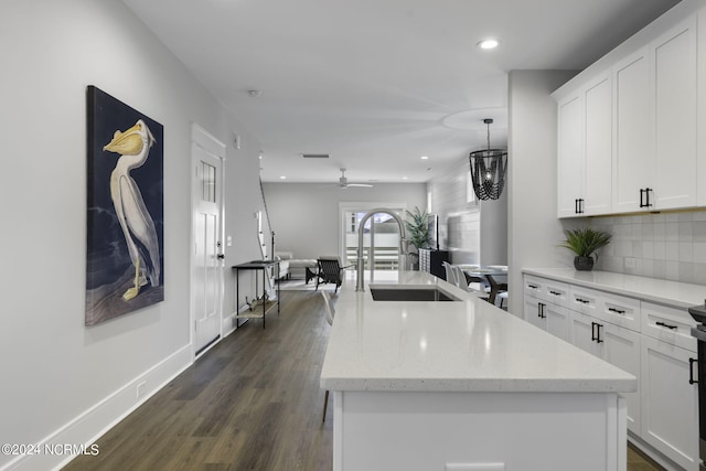 kitchen featuring a center island with sink, white cabinetry, sink, and dark wood-type flooring