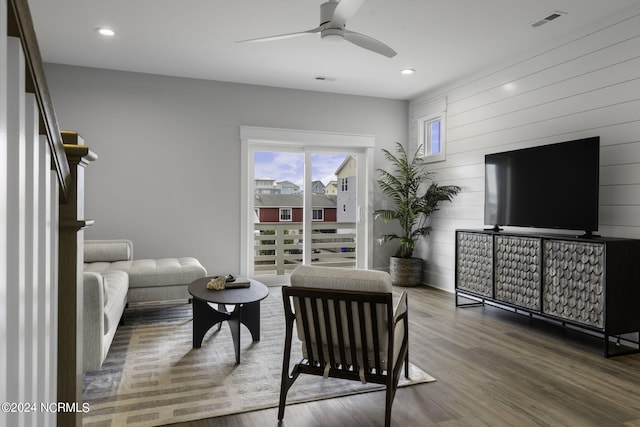 living room featuring wooden walls, ceiling fan, and hardwood / wood-style flooring