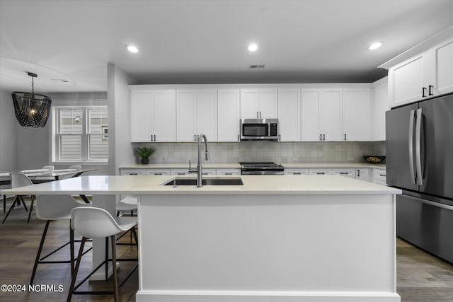 kitchen featuring appliances with stainless steel finishes, a center island with sink, and white cabinets