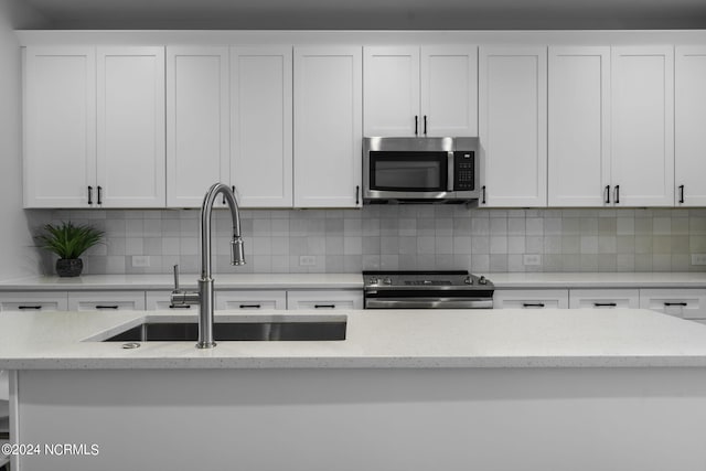 kitchen featuring stainless steel appliances, sink, and white cabinetry