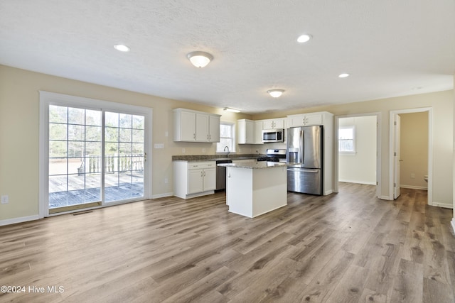 kitchen featuring white cabinets, a center island, stainless steel appliances, and a wealth of natural light