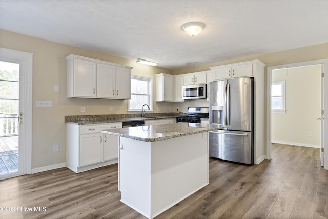 kitchen featuring white cabinets, plenty of natural light, a kitchen island, and appliances with stainless steel finishes