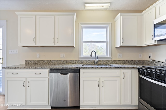 kitchen with white cabinets, sink, dark stone countertops, a textured ceiling, and appliances with stainless steel finishes