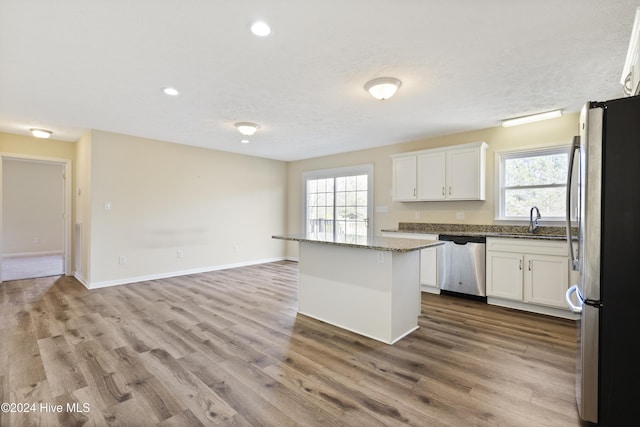 kitchen with a wealth of natural light, white cabinets, stainless steel appliances, and a kitchen island