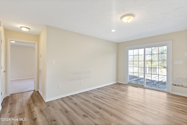 spare room featuring light hardwood / wood-style floors and a textured ceiling