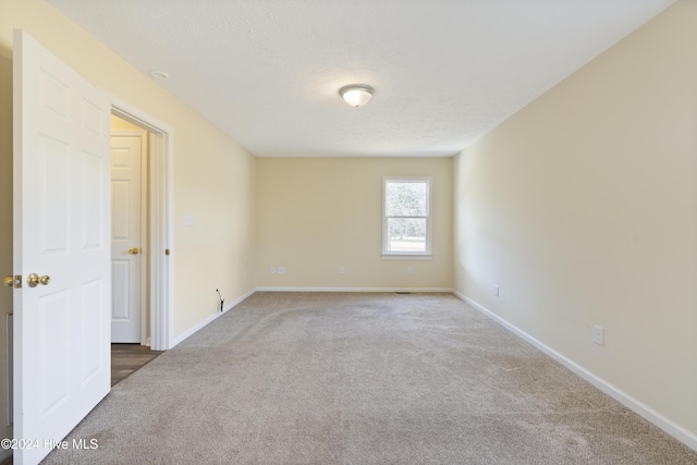 carpeted empty room with a textured ceiling