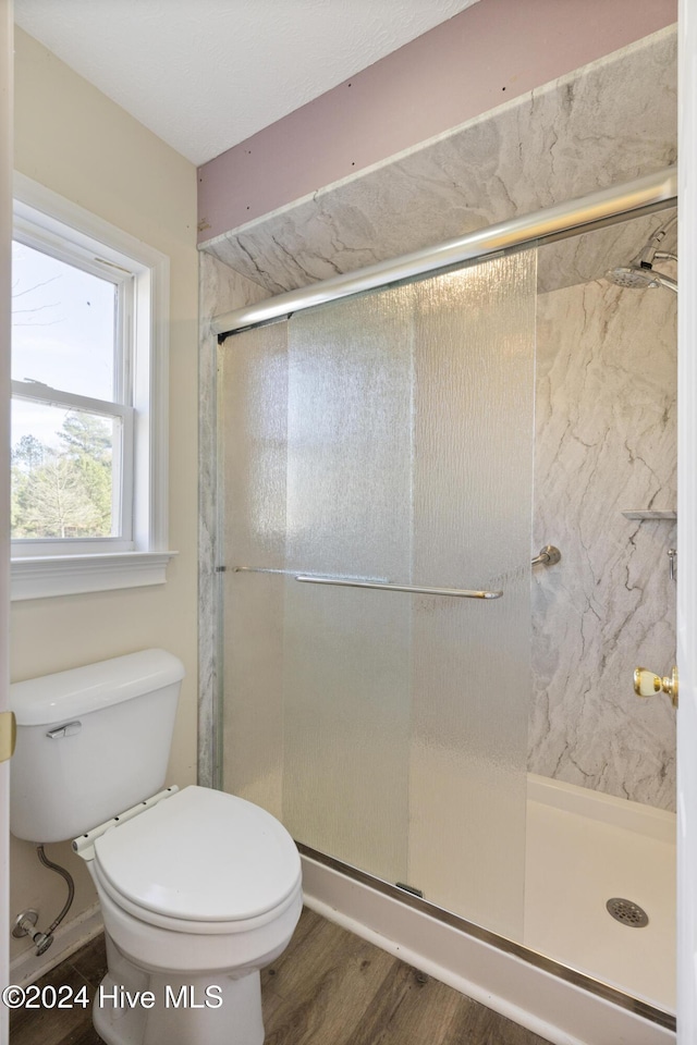 bathroom with wood-type flooring, toilet, and walk in shower