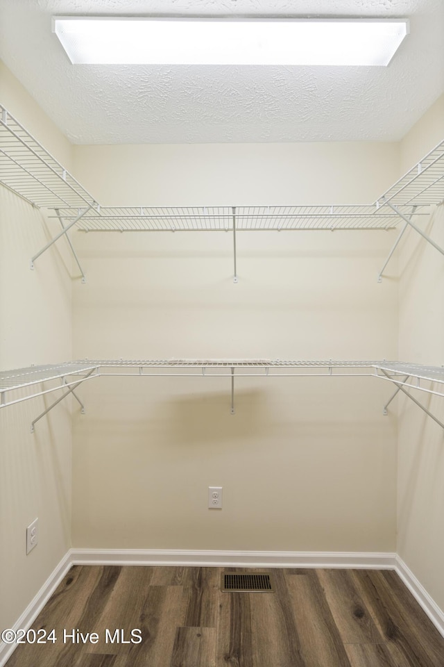 walk in closet with dark wood-type flooring