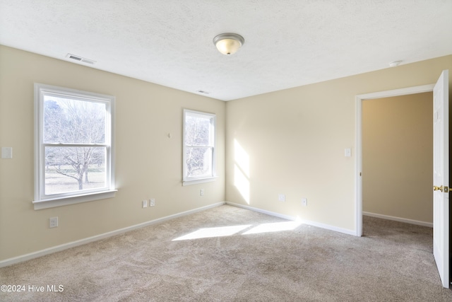 carpeted empty room featuring a textured ceiling