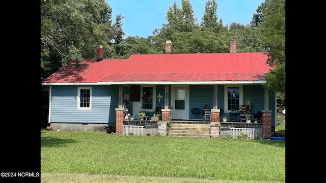 view of front facade with metal roof, a porch, crawl space, and a front lawn