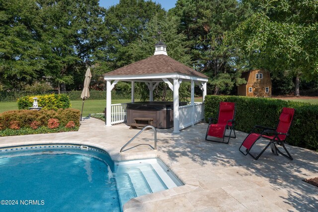 view of pool with a hot tub, an outbuilding, a patio, and a gazebo