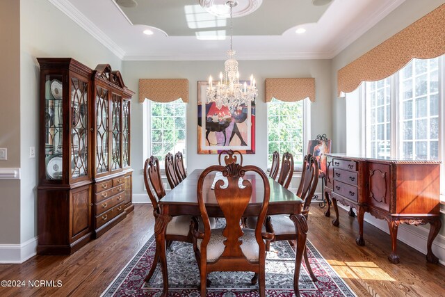 dining space with ornamental molding, dark hardwood / wood-style flooring, a healthy amount of sunlight, and a notable chandelier