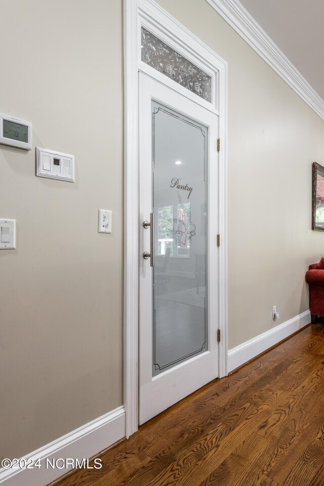 doorway to outside featuring dark wood-type flooring and crown molding