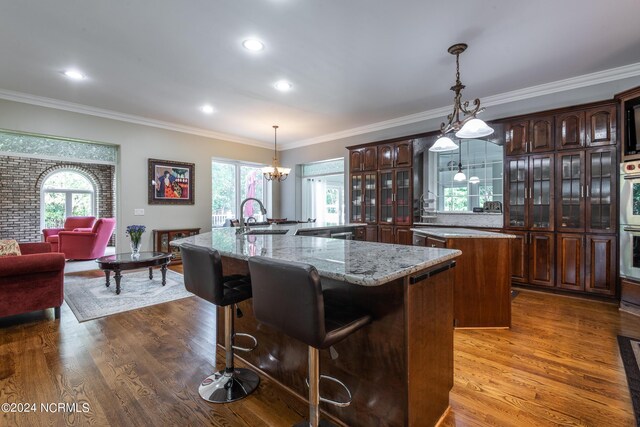 kitchen featuring hardwood / wood-style flooring, a center island with sink, crown molding, and sink