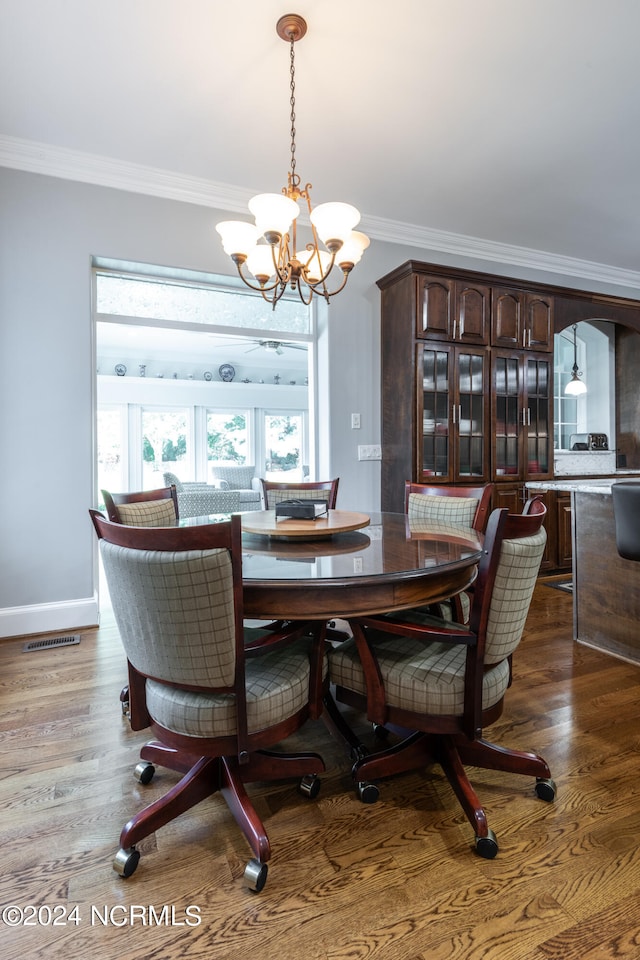 dining area featuring crown molding, wood-type flooring, and a chandelier