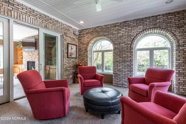 sitting room with crown molding, brick wall, a large fireplace, and carpet flooring