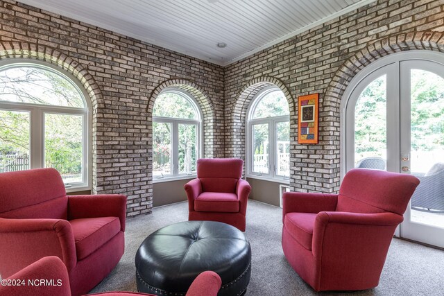 interior space with french doors, carpet flooring, a wealth of natural light, and brick wall