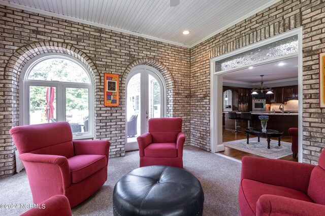 carpeted living room with a wealth of natural light and brick wall