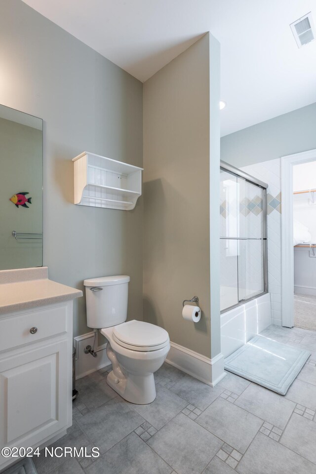 full bathroom featuring vanity, toilet, and bath / shower combo with glass door