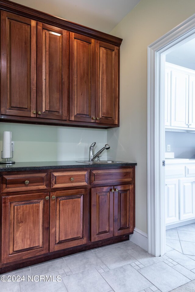 kitchen with dark stone counters, light tile patterned floors, and sink