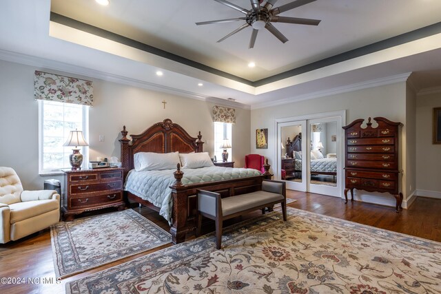 bedroom featuring crown molding, ceiling fan, a tray ceiling, and hardwood / wood-style flooring