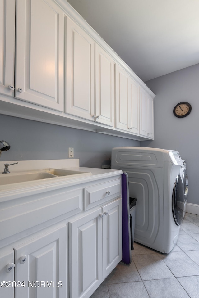 clothes washing area with cabinets, sink, light tile patterned floors, and washing machine and dryer