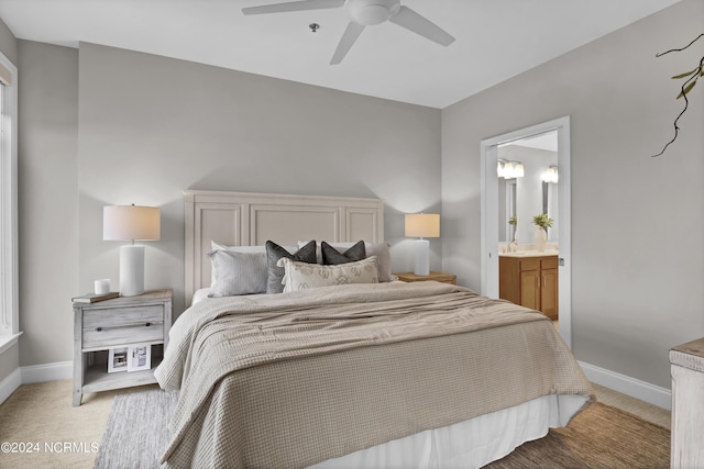 bedroom with baseboards, connected bathroom, and light colored carpet