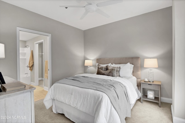 bedroom featuring light carpet, ceiling fan, baseboards, and connected bathroom