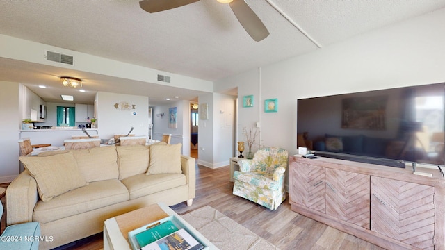 living room featuring a textured ceiling, light hardwood / wood-style flooring, and ceiling fan