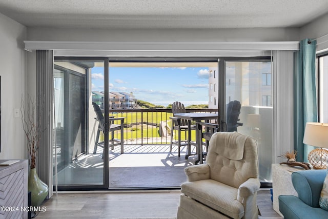 doorway to outside featuring a textured ceiling and light hardwood / wood-style flooring