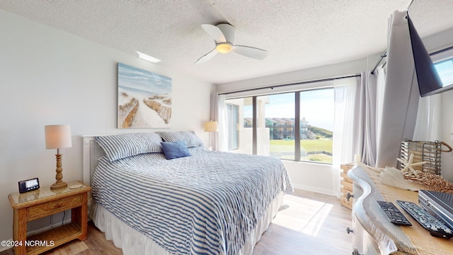 bedroom featuring light wood-type flooring, a textured ceiling, and ceiling fan