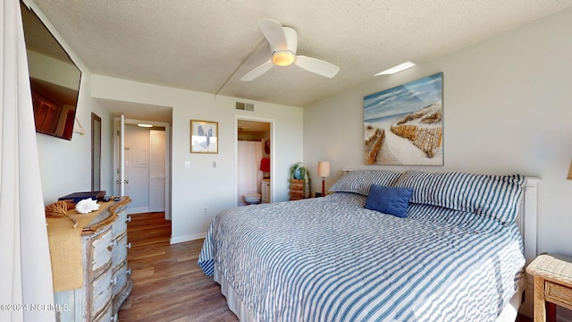 bedroom featuring a textured ceiling, wood-type flooring, ensuite bathroom, and ceiling fan