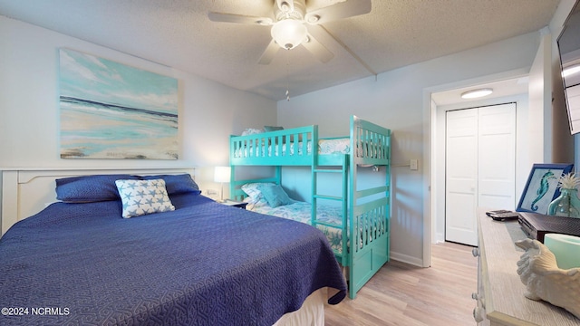 bedroom with a textured ceiling, ceiling fan, a closet, and light hardwood / wood-style floors